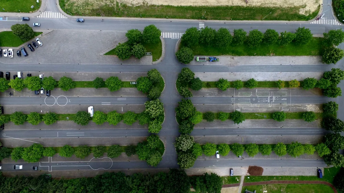 Parkplatzanlage mit Baumreihen und Grünstreifen aus der Luft