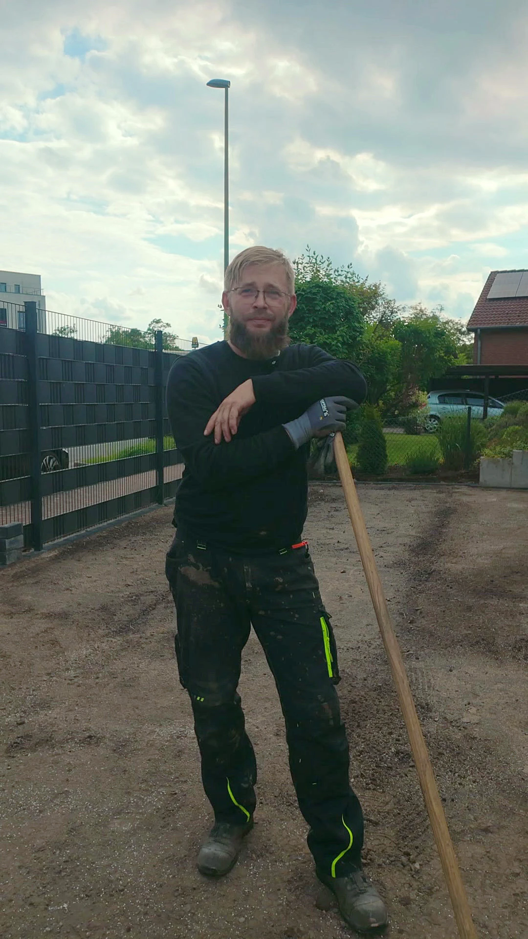 Roman Weiss, Inhaber von Weiss Garten- und Landschaftsbau, mit Rechen auf einer vorbereiteten Fläche im Garten